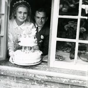 Bride and Groom at the window, displaying their wedding cake