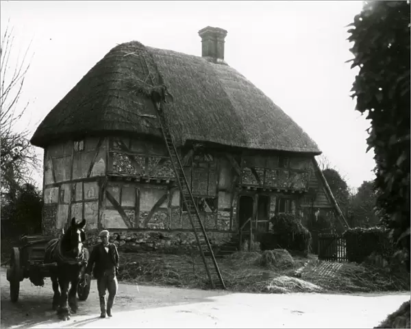 Bignor General Shop with thatcher at work, February 1938