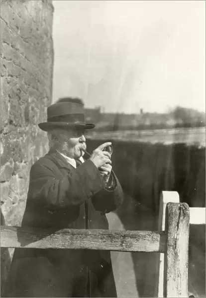 Gentleman lighting his pipe with a magnifying glass, March 1933