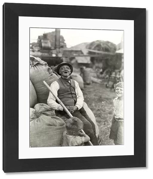 Old character with young boys, threshing machinery in the background, 1932