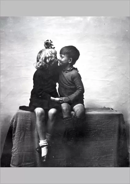 Young boy and girl kissing under mistletoe