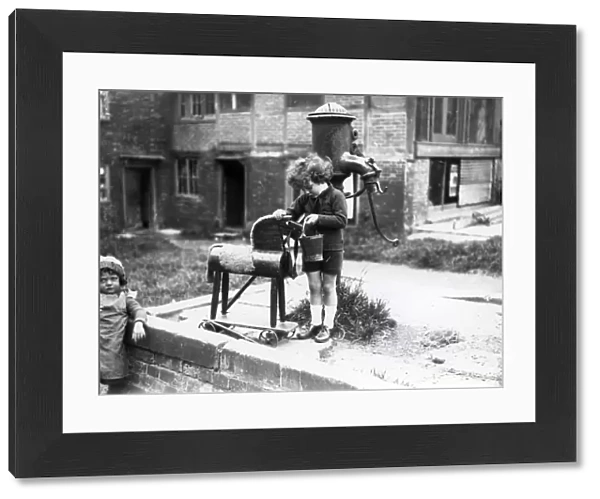 Young child pretending to water a wooden horse, August 1923