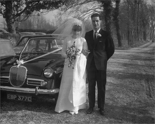 Bride and Groom standing by wedding car