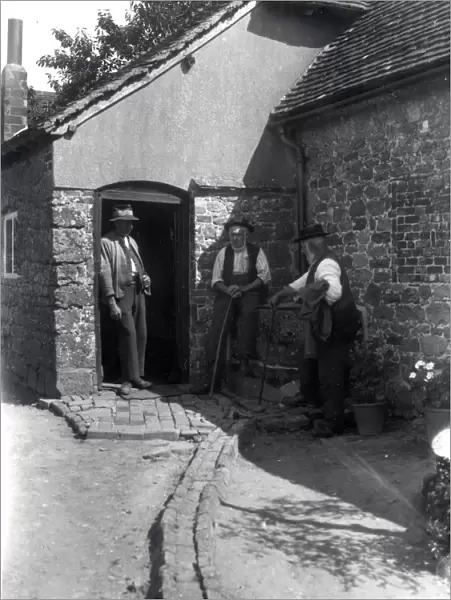 Three country gentlemen chatting in a farmyard at Upperton, Sussex. August 1936