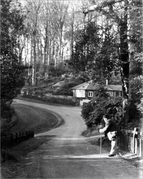 Gentleman leaning on stick in country lane, January 1935