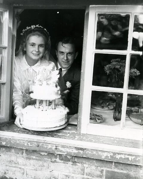 Bride and Groom at the window, displaying their wedding cake