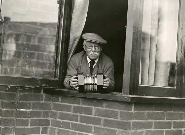 Elderly gentleman leaning out of the window with concertina, April 1938