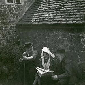 Three country folk discussing the news in a newspaper, Upperton, Sussex
