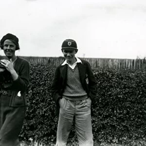 Young boy in cap and young lady with camera in field, September 1938