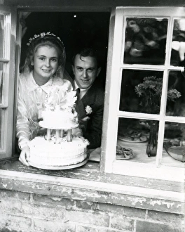 Bride and Groom at the window, displaying their wedding cake Bride and Groom at the window, displaying their wedding cake