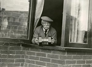 Elderly gentleman leaning out of the window with concertina, April 1938 Elderly gentleman leaning out of the window with concertina, April 1938
