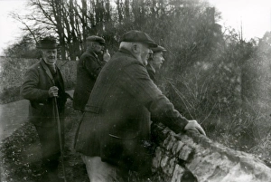 Elderly gentlemen leaning over flint wall