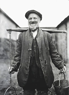 Farm worker with buckets on a yoke, Lavant, Sussex Farm worker with buckets on a yoke, Lavant, Sussex