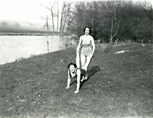 Images Dated 6th October 2014: Two girls doing a wheelbarrow pose by the riverbank in Stopham, March 1938