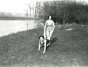 Two girls doing a wheelbarrow pose by the riverbank in Stopham, March 1938 Two girls doing a wheelbarrow pose by the riverbank in Stopham, March 1938