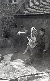 Three people chatting in the sunshine on a farm at Upperton, Sussex Three people chatting in the sunshine on a farm at Upperton, Sussex