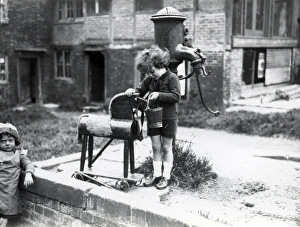 Bucket Prints: Young child pretending to water a wooden horse, August 1923